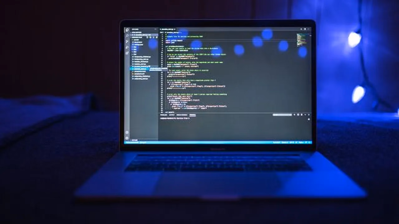 Laptop glowing in a dark room with code on screen during a debugging session