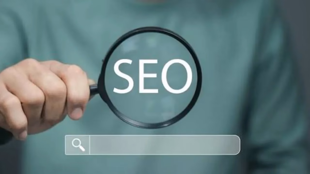 A hand holding a magnifying glass over the word SEO above a search bar, representing SEO-friendly blog writing