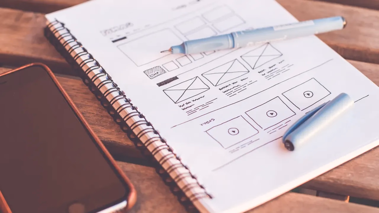 Notebook with hand-drawn wireframe sketches planning a custom WordPress theme layout